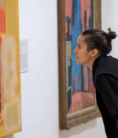 Dark-haired person looking at painting. Photo by Della Perrone.